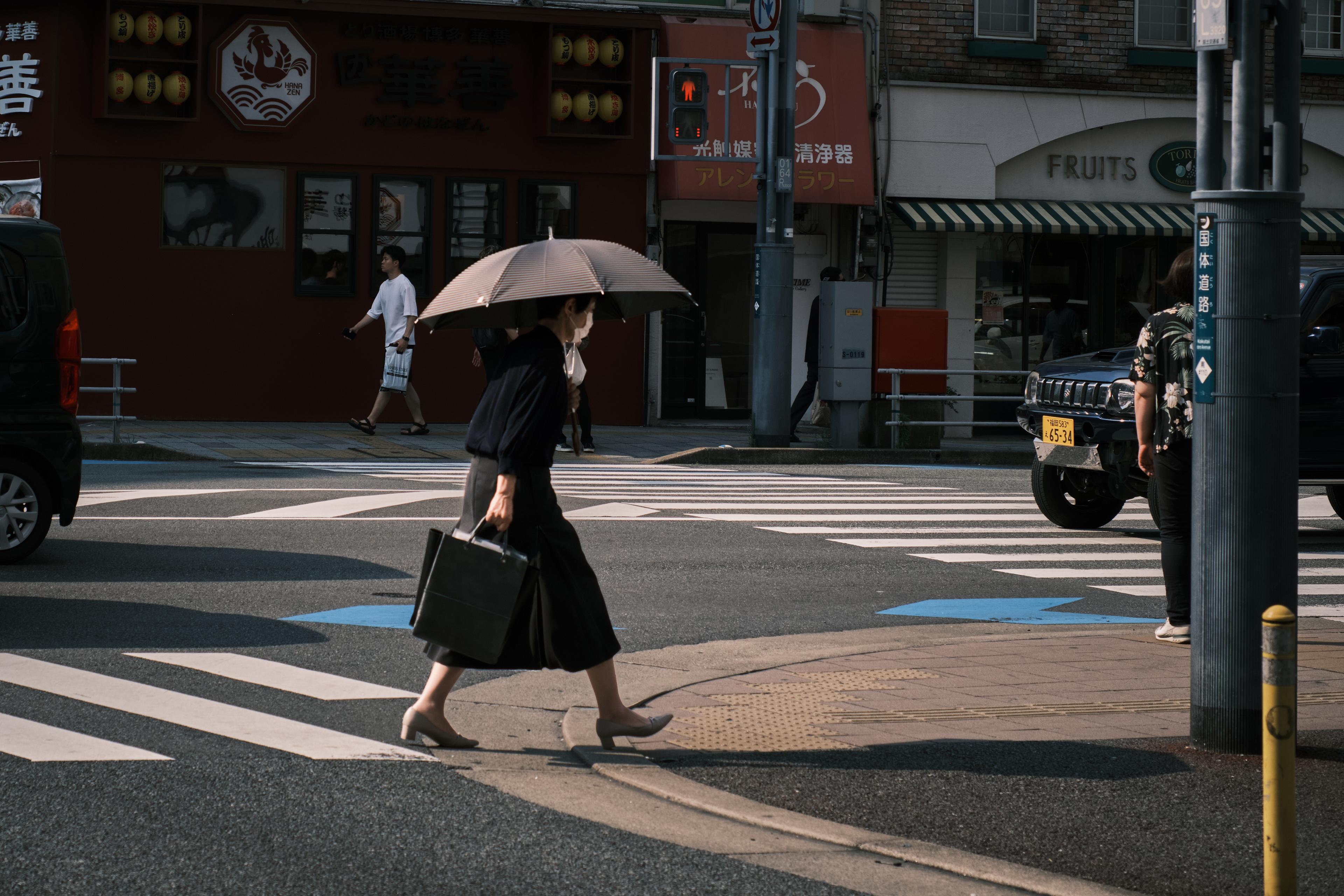 a woman in black crossing the street